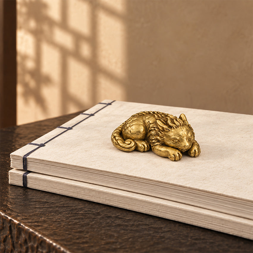 Gold-toned Qilin brass paperweight resting on a bound book.