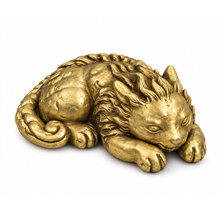 Gold-toned Qilin brass paperweight in a curled resting pose, on a white background.